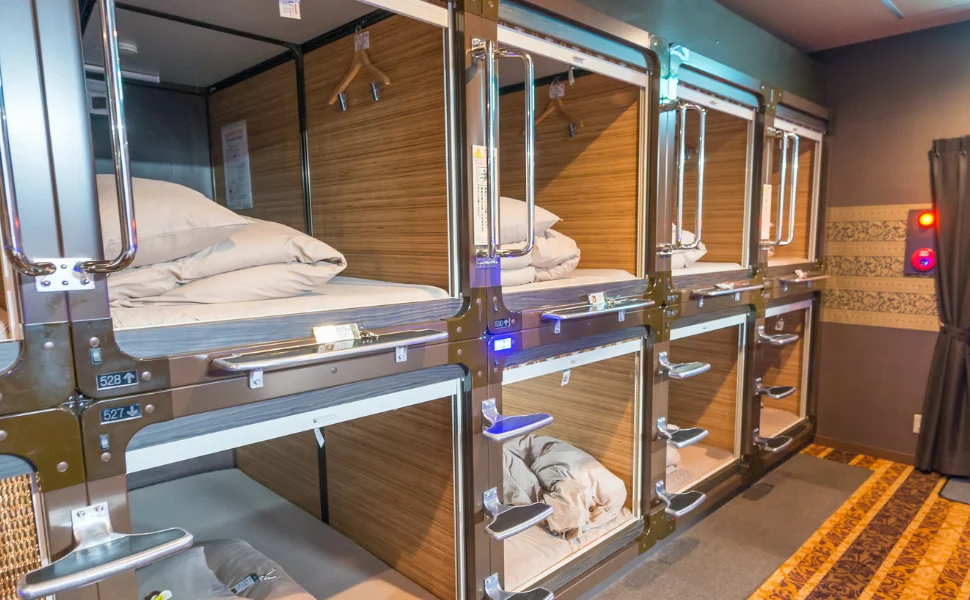 A lit corridor of sleeping pods in a capsule hotel