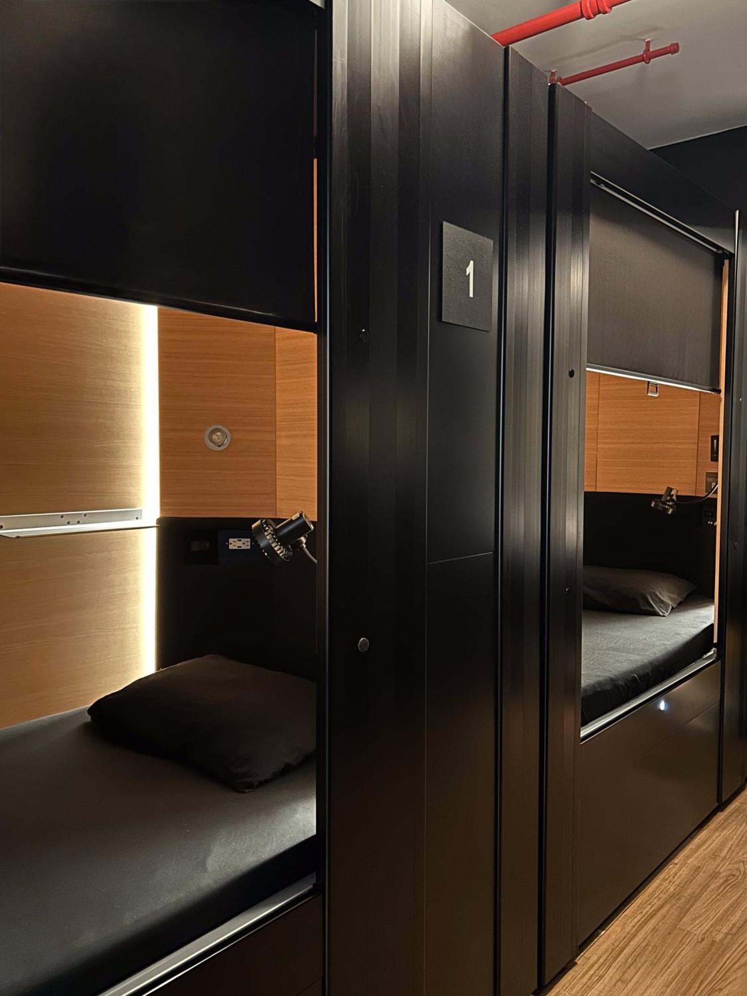 A sleeping pod with a curtain drawn back on a quiet floor at Nap York