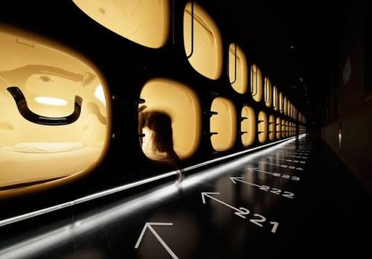Rows of white sleeping pods on a lit corridor at nine hours Sendai